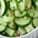 A fresh cucumber salad with sliced cucumbers, red onions, and a tangy vinaigrette dressing.