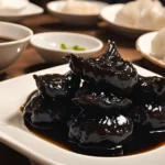 A bowl of Din Tai Fung dumplings with a dipping sauce made from black vinegar and soy sauce